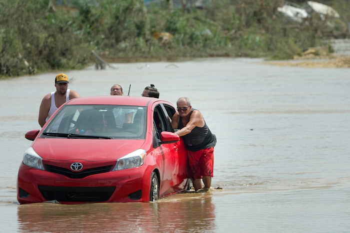 Residents push a car in a flooded road after the passing of Hurricane Maria, in Toa Baja, Puerto Rico, Friday, September 22, 2017. Because of the heavy rains brought by Maria, thousands of people were evacuated from Toa Baja after the municipal government opened the gates of the Rio La Plata Dam. (AP Photo/Carlos Giusti)