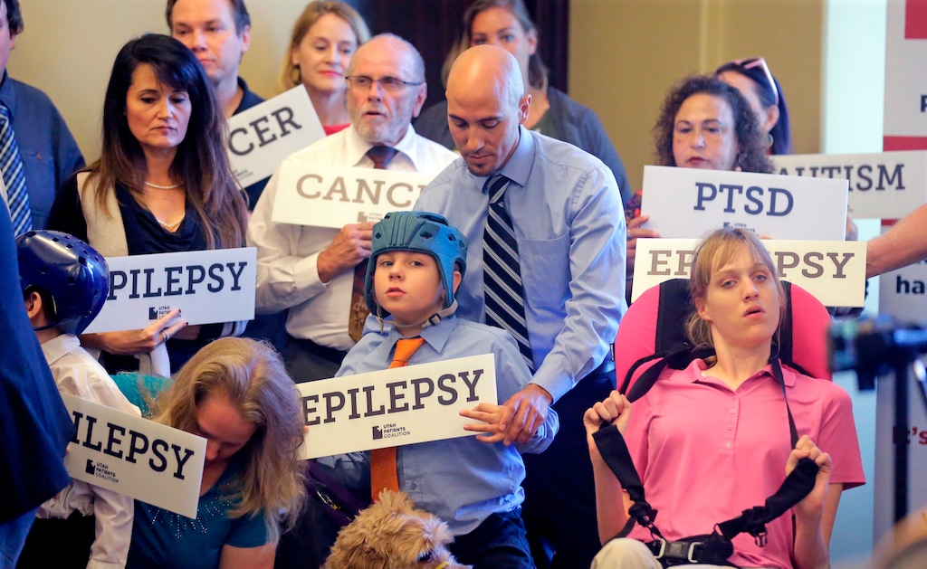 FILE - In this June 26, 2017, file photo, Davis Cromar, center, holds his son Holden, 10, who suffers from epilepsy, while standing with other patients, caregivers and supporters during the Utah Patients Coalition news conference, in Salt Lake City. Voters in the deep red states of Utah and Oklahoma will have a chance to legalize medical marijuana through ballot initiatives that offer the latest illustration of how quickly the United States is leaving behind taboos about the drug. (AP Photo/Rick Bowmer, File)