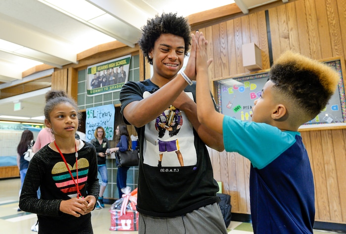 (Francisco Kjolseth  |  The Salt Lake Tribune)  With sister Mya, 8, Kearns High sophomore Keeven Wilson, 16, gets a high-five from his brother Kamani, 9, after being announced as the Granite School District's Absolutely Incredible Kid award winner during the school farewell assembly on Tuesday, May 22, 2018. Wilson who had a particularly difficult home life, to the point that he and his siblings were taken away from his parents and near universal F's during his junior high days, turned his life around. With the help of a new foster family, teachers and his football coach, he is now an honor roll student and thinking of studying psychology in college.