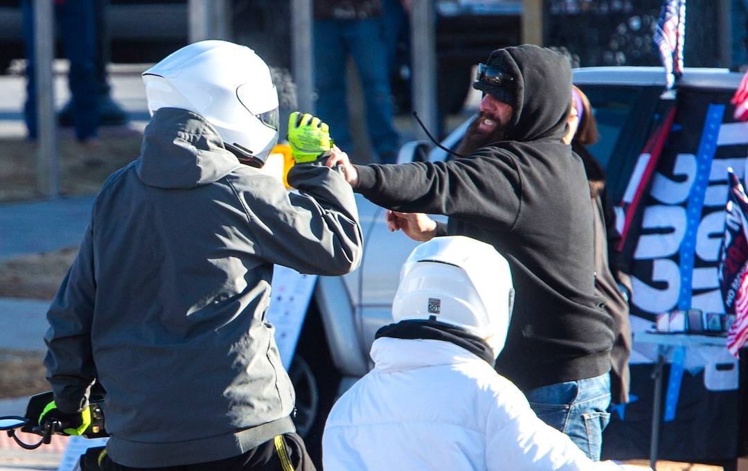 (Rick Egan | The Salt Lake Tribune) A Trump protester waving a flag in the street grabs a man on a scooter, during a Trump rally at the Utah State Capitol on Wednesday, Jan. 6, 2021.