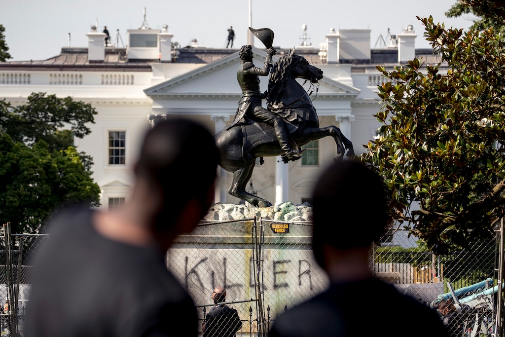 Anthony Davis of Upper Marlboro, Md., left, speaks to his son Jonathan, 13, right, as they look at a statue President Andrew Jackson in Lafayette Park, Tuesday, June 23, 2020, in Washington, with the word "Killer" spray painted on its base. Protesters tried to topple the statue Monday night. President Tump had tweeted late Monday that those who tried to topple the statue of President Andrew Jackson in Lafayette Park across the street from the White House faced 10 years in prison under the Veteran's Memorial Preservation Act. (AP Photo/Andrew Harnik)