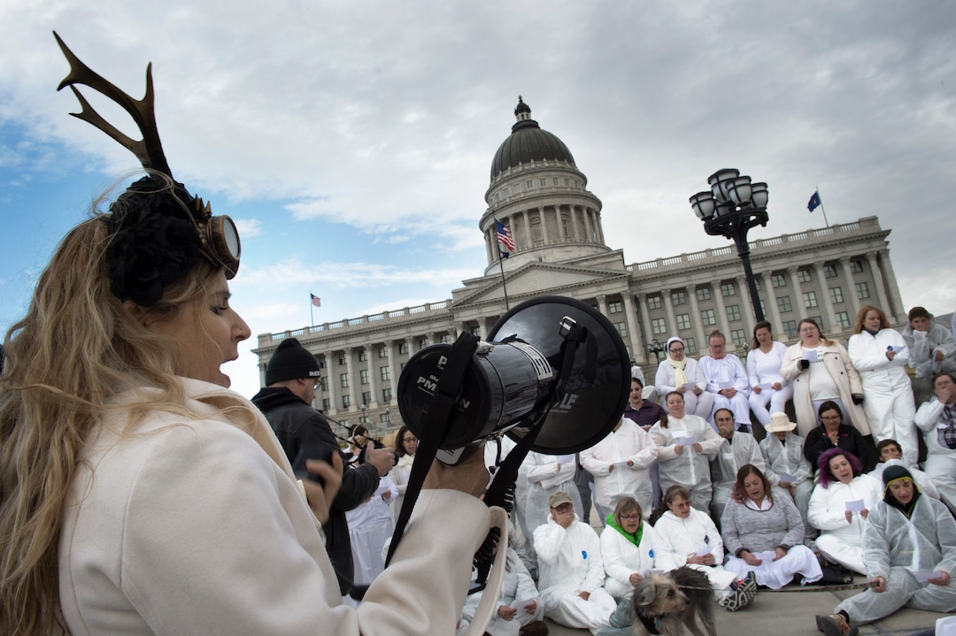(Scott Sommerdorf   |  The Salt Lake Tribune)   Melissa Bond helped read the comments made famous from the Access Hollywood tape of Trump speaking about how he approached women while speaking with Billy Bush. Earlier these protesters dressed in white jumpsuits spelled out "GO HOME TRUMP" on the south lawn of the Utah State Capitol, Sunday, December 3, 2017, during a protest organized by artist Cat Palmer ahead of Trump's visit Monday. 