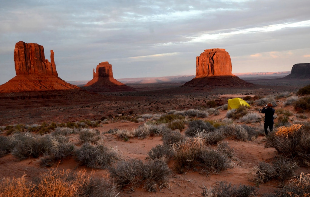 Visitors at the Monument Valley Tribal Park Visitors Center in Oljato-Monument Valley, Az., turned out on Wednesday, March 29, 2023 to watch the Mitten Shadow Event during which the West Mitten Butte casts a shadow over the East Mitten Butte. A sunset spectacle featuring two mitten-shaped rock formations played out this week at Monument Valley on the Navajo Nation, bordering Arizona and Utah. Twice a year, in late March and mid-September, spectators, photographers and videographers get a visual treat. As the sun sinks, the West Mitten Butte's shadow crawls across the desert valley floor before climbing up the side of the East Mitten Butte. (AP Photo/Vyto Starinskas)