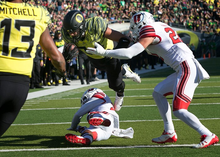 Oregon tight end Cam McCormick dives for a touchdown over Utah's Julian Blackmon, bottom and Chase Hansen, right, during the first quarter of an NCAA college football game Saturday, Oct. 28, 2017, in Eugene, Ore. (AP Photo/Chris Pietsch)