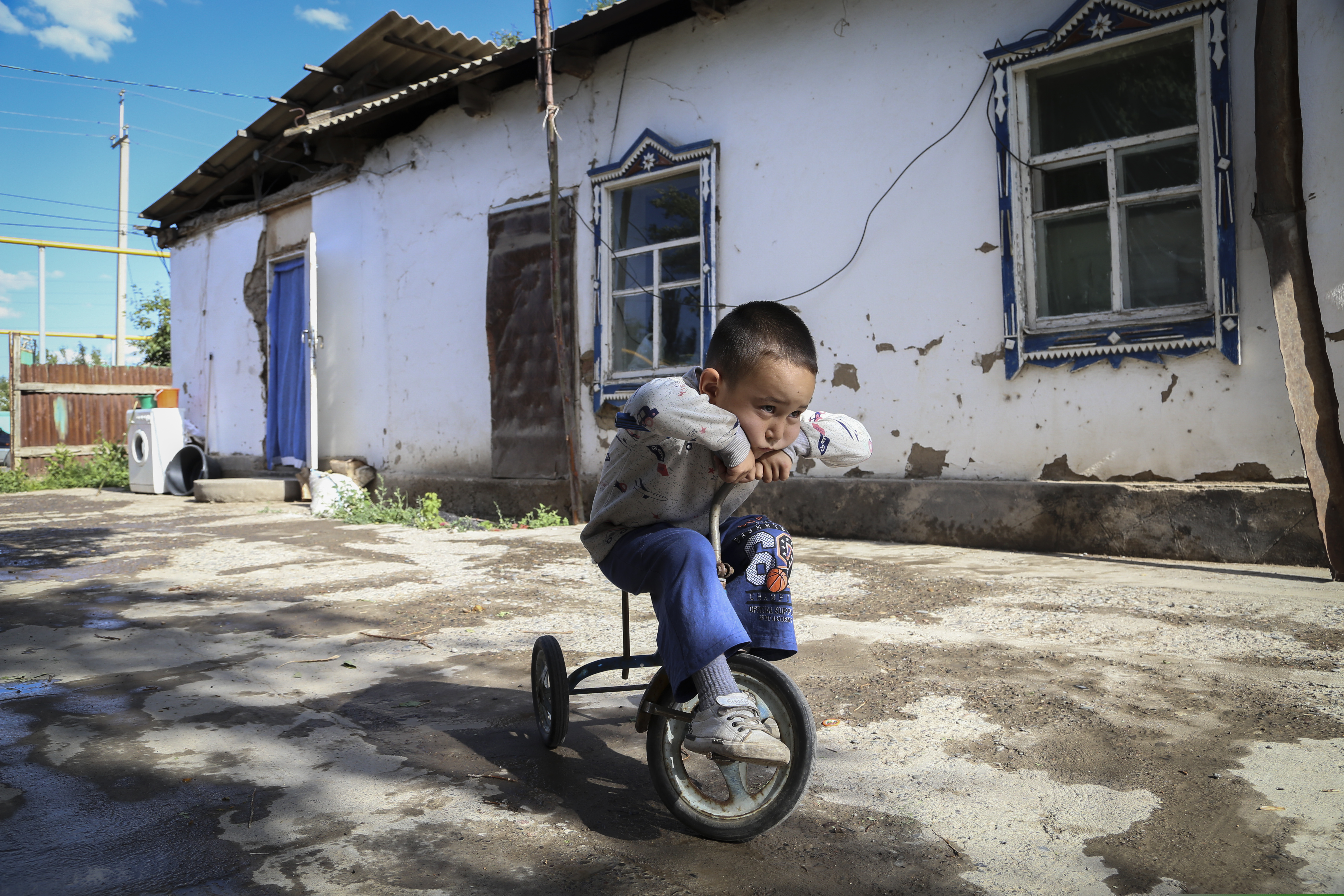 (AP Photo/Mukhit Toktassyn) Alif Baqytali plays on a tricycle at his home in Shonzhy, Kazakhstan on Saturday, June 13, 2020. Baqytali's mother, Gulnar Omirzakh, a Chinese-born ethnic Kazakh, says she was forced to get an intrauterine contraceptive device, and that authorities threatened to detain her if she didn't pay a large fine for giving birth to Alif, her third child.