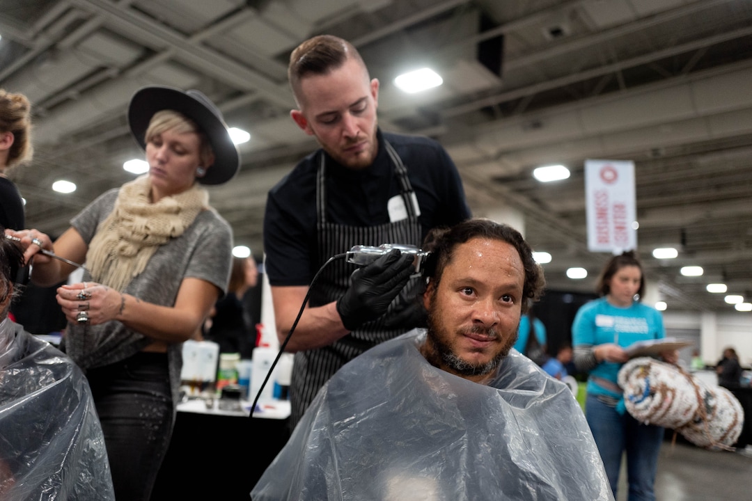 (Trent Nelson  |  The Salt Lake Tribune)Mike Ibarra gets a haircut from Cody McCluskey at Project Homeless Connect, where community volunteers to provide services for individuals and families experiencing homelessness, at the Salt Palace Convention Center in Salt Lake City on Friday Oct. 25, 2019. At left is Ariel Betancourt.