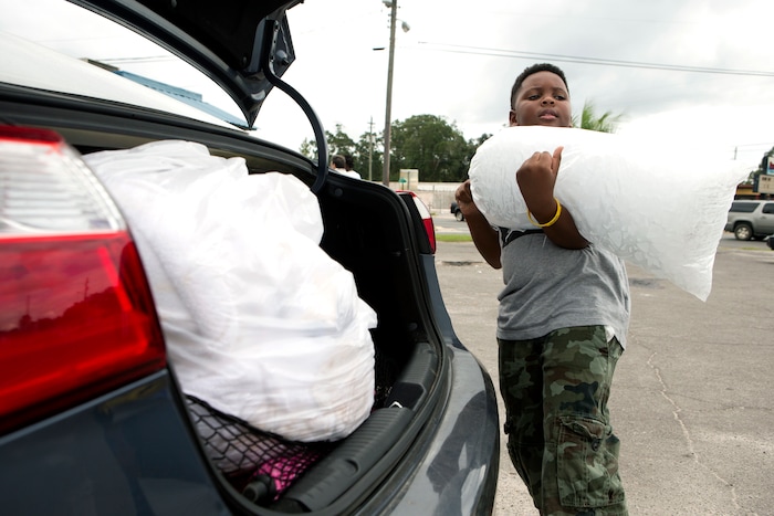 (Joshua Boucher | News Herald | The Associated Press) Xavier McKenzie puts a twenty pound bag of ice into his family's car in Panama City, Fla., as Hurricane Michael approaches on Tuesday, Oct.9, 2018. He and his family do not live in a storm surge area, and instead prepared for losing power for days.