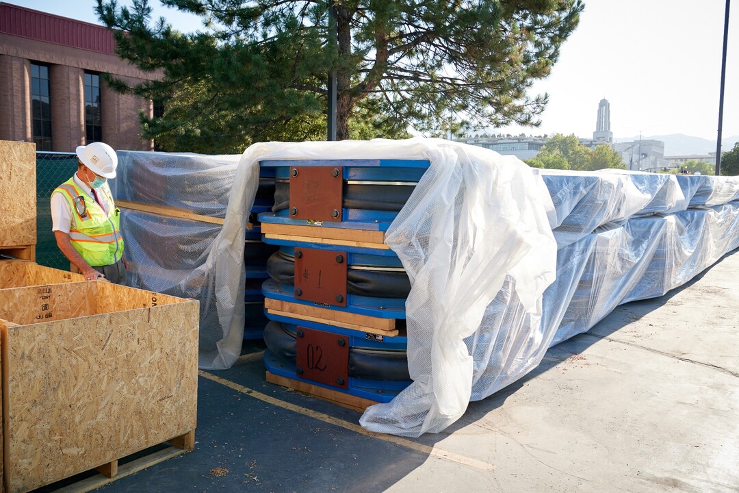 (Photo courtesy The Church of Jesus Christ of Latter-day Saints) A construction worker looks at a pile of base isolators. The 98 base isolators, designed to limit motion of the 187-million-pound temple in a high magnitude earthquake, can withstand pressure nearly five times the weight of the temple. They will be installed when new footings are made underneath the existing temple foundation, which is now undergoing the strengthening and reinforcement phase.