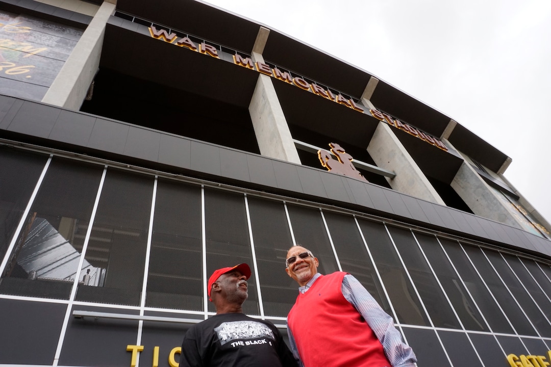 (Mead Gruver | AP Photo) In this Wednesday, Sept. 11, 2019 photo Black 14 members Ron Hill, left, and Lionel Grimes, right, stand outside War Memorial Stadium at the University of Wyoming. Hill and Grimes were members of the Black 14, a group of black players dismissed from the Cowboys football team in 1969 for seeking to protest racism by wearing black armbands in a game against Brigham Young University. The university plans to dedicate a plaque honoring the group at the stadium on Friday.