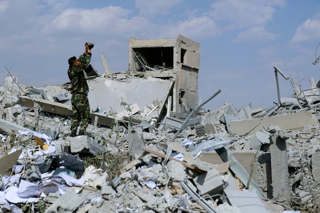 A Syrian soldier films the damage of the Syrian Scientific Research Center which was attacked by U.S., British and French military strikes to punish President Bashar Assad for suspected chemical attack against civilians, in Barzeh, near Damascus, Syria, Saturday, April 14, 2018. The Pentagon says none of the missiles filed by the U.S. and its allies was deflected by Syrian air defenses, rebutting claims by the Russian and Syrian governments. Lt. Gen. Kenneth McKenzie, the director of the Joint Staff at the Pentagon, also says there also is no indication that Russian air defense systems were employed early Saturday in Syria. (AP Photo/Hassan Ammar)