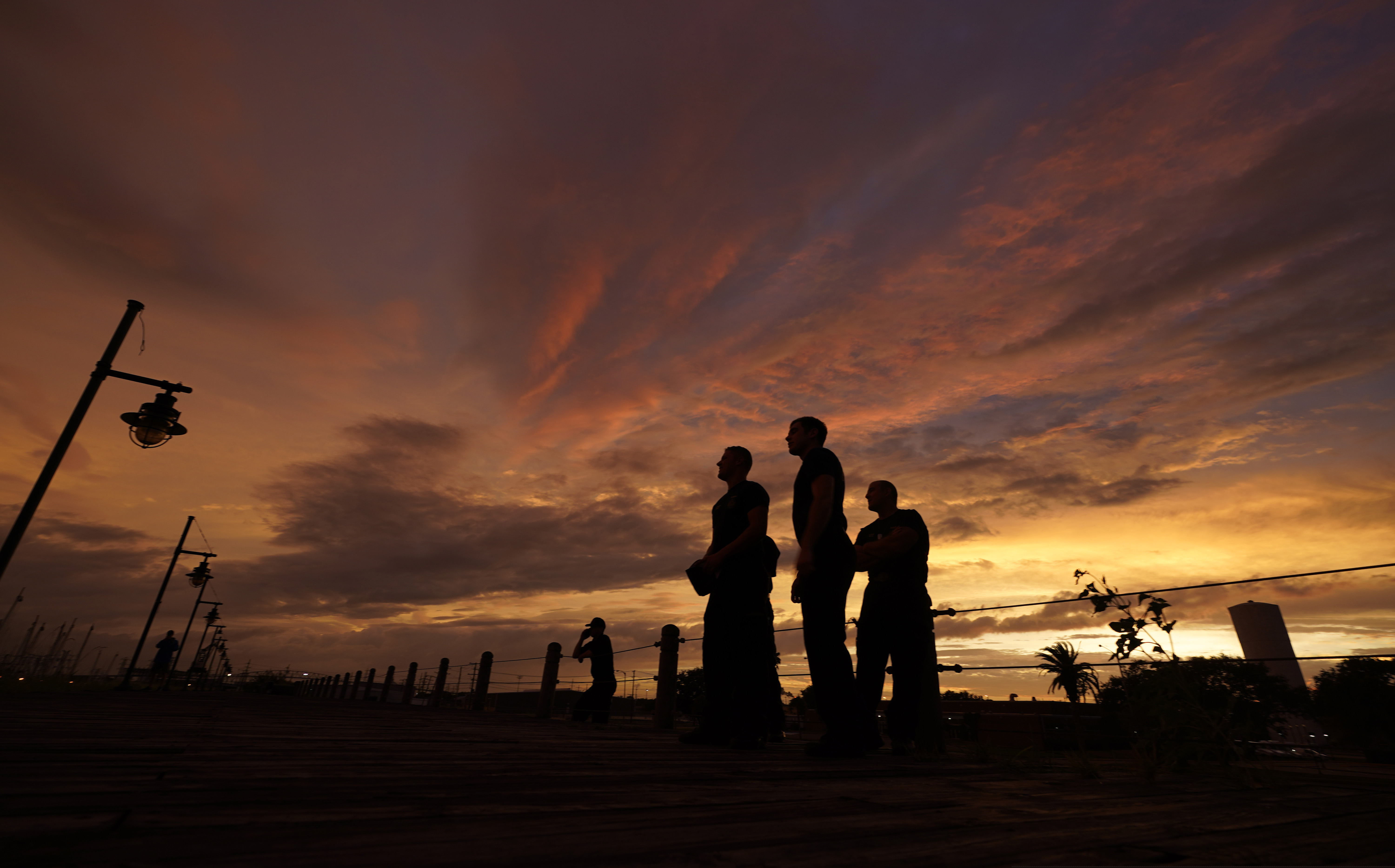 Port Arthur firefighters stare at a sea wall at sunset as they wait for Hurricane Laura to make landfall, Wednesday, Aug. 26, 2020, in Port Arthur, Texas. (AP Photo/Eric Gay)