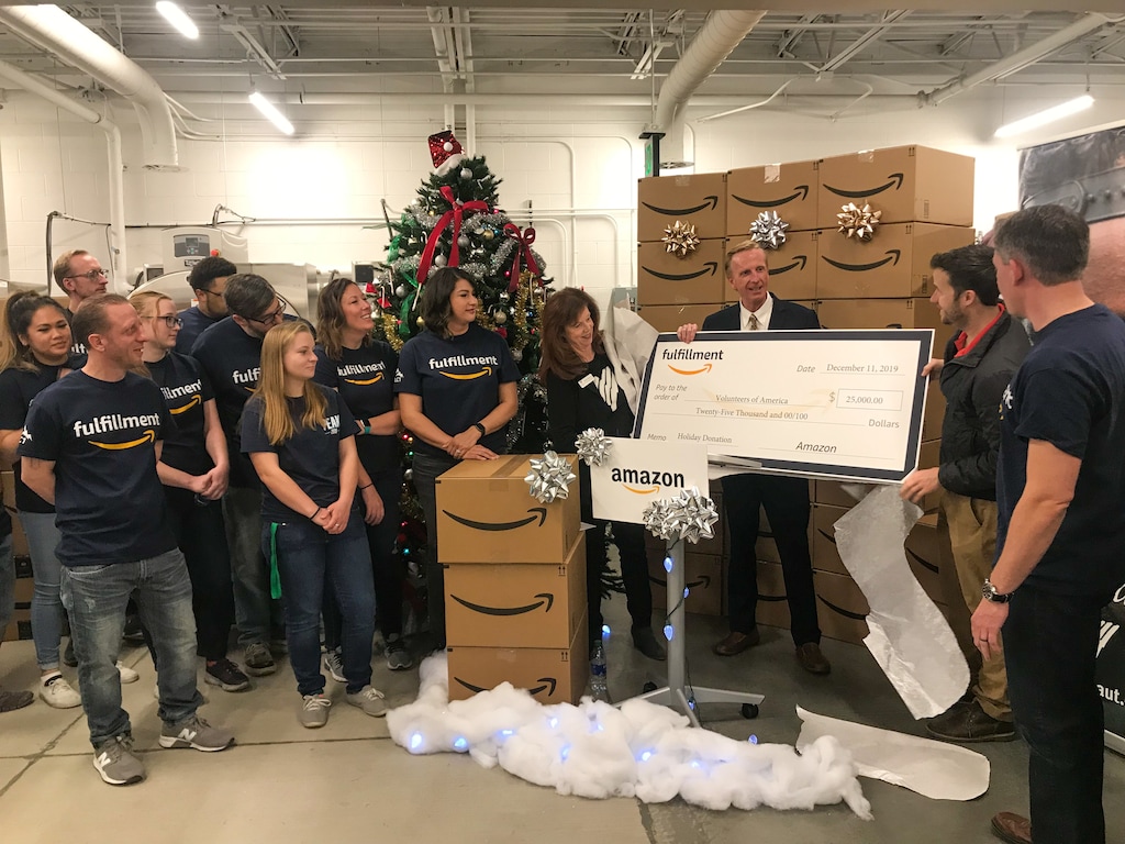 (Photo courtesy of Lauren Littlefield) Amazon fulfillment and delivery employees look on as company officials pass a check for $25,000 to VOA leaders in early December.