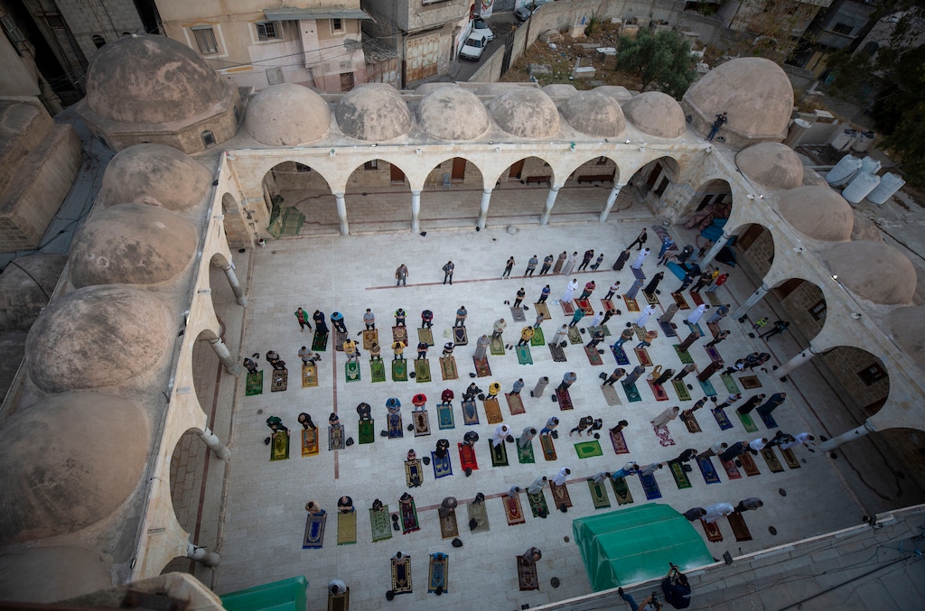 (Khalil Hamra | AP Photo) Muslims wearing face masks attend the Eid al-Fitr prayers outside a mosque in Gaza City, Sunday, May 24, 2020.