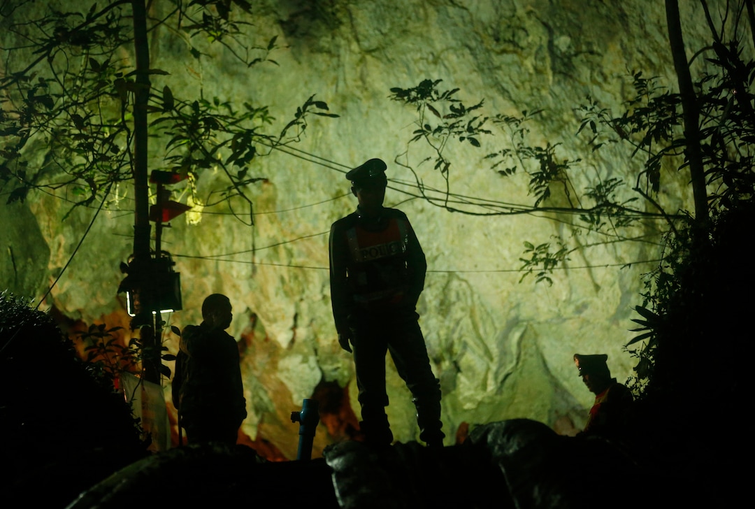 Thai police stand in front of the entrance to a cave complex where 12 boys and their soccer coach went missing, in Mae Sai, Chiang Rai province, in northern Thailand, Monday, July 2, 2018. Rescue divers are advancing in the main passageway inside the flooded cave in northern Thailand where the boys and their coach have been missing more than a week. (AP Photo/Sakchai Lalit)