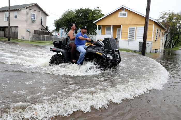 (Jennifer Reynolds | The Galveston County Daily News via AP) Galveston, Texas, residents ride an all terrain vehicle down 50th Street on Saturday, Aug. 26, 2017, as they survey the flooding from Hurricane Harvey in their neighborhood.