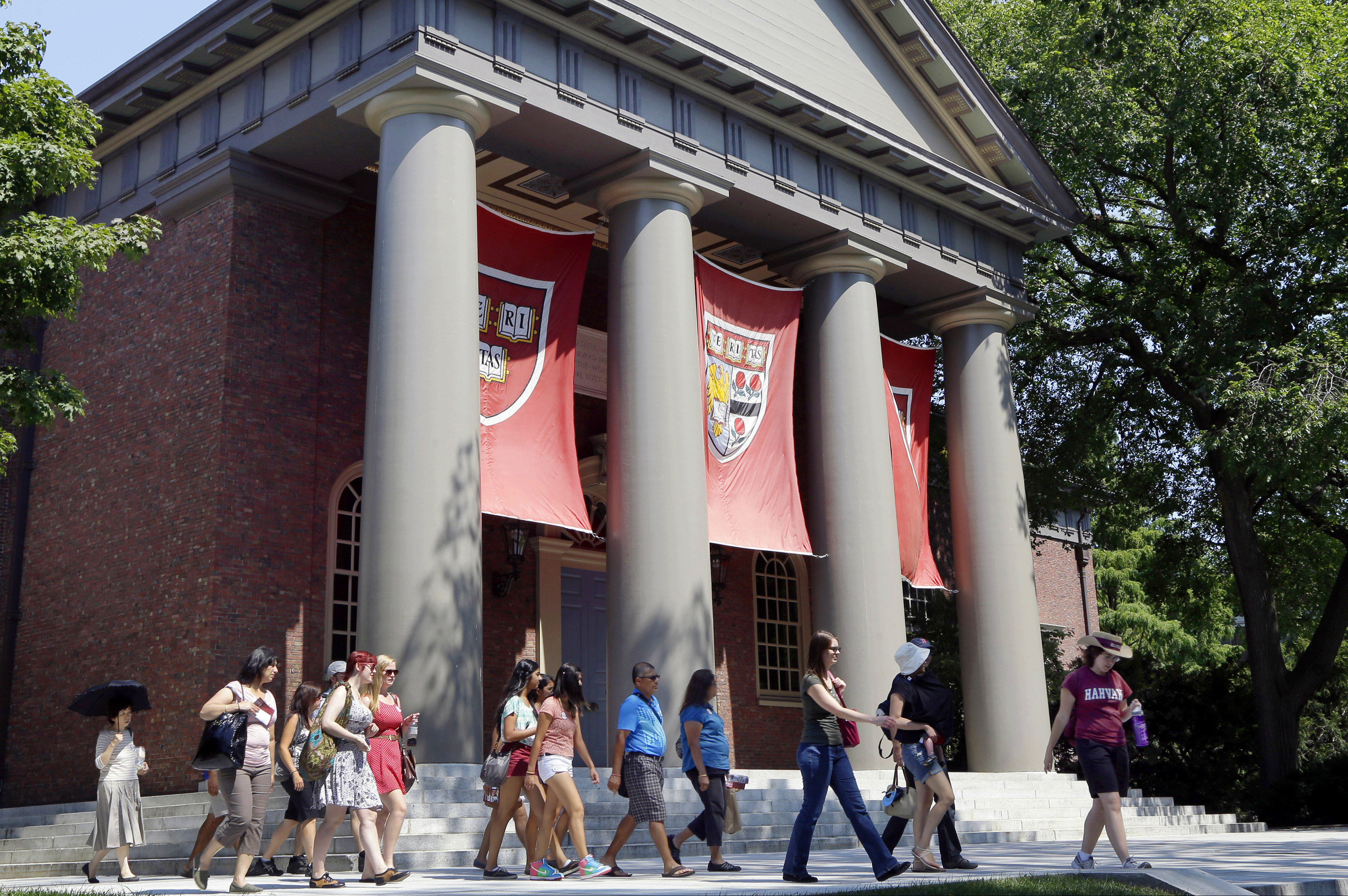 (Elise Amendola | AP file photo) A tour group walks through the campus of Harvard University in Cambridge, Mass., in 2012.