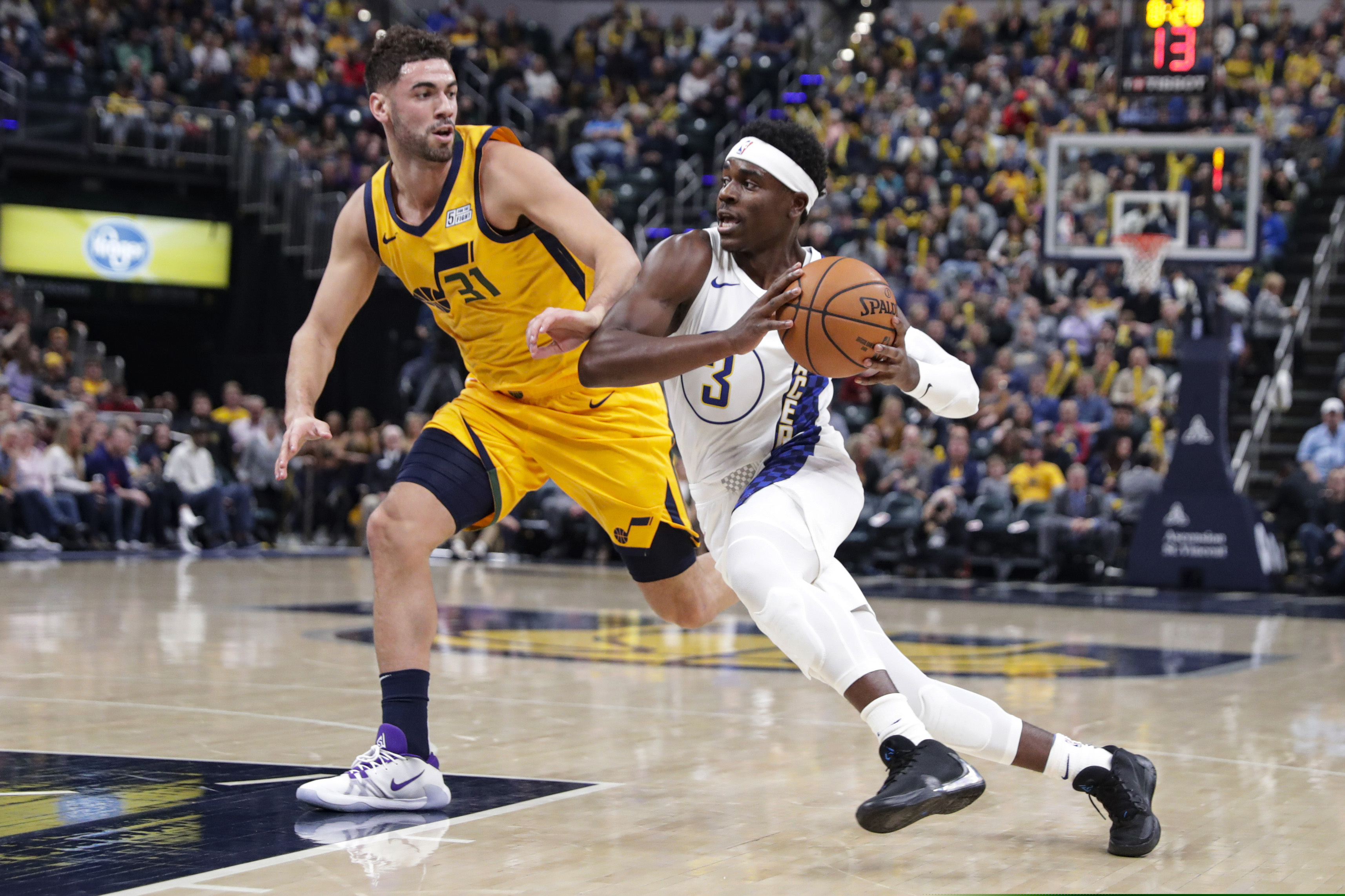 Indiana Pacers guard Aaron Holiday (3) drives on Utah Jazz forward Georges Niang (31) during the first half of an NBA basketball game in Indianapolis, Wednesday, Nov. 27, 2019. (AP Photo/Michael Conroy)