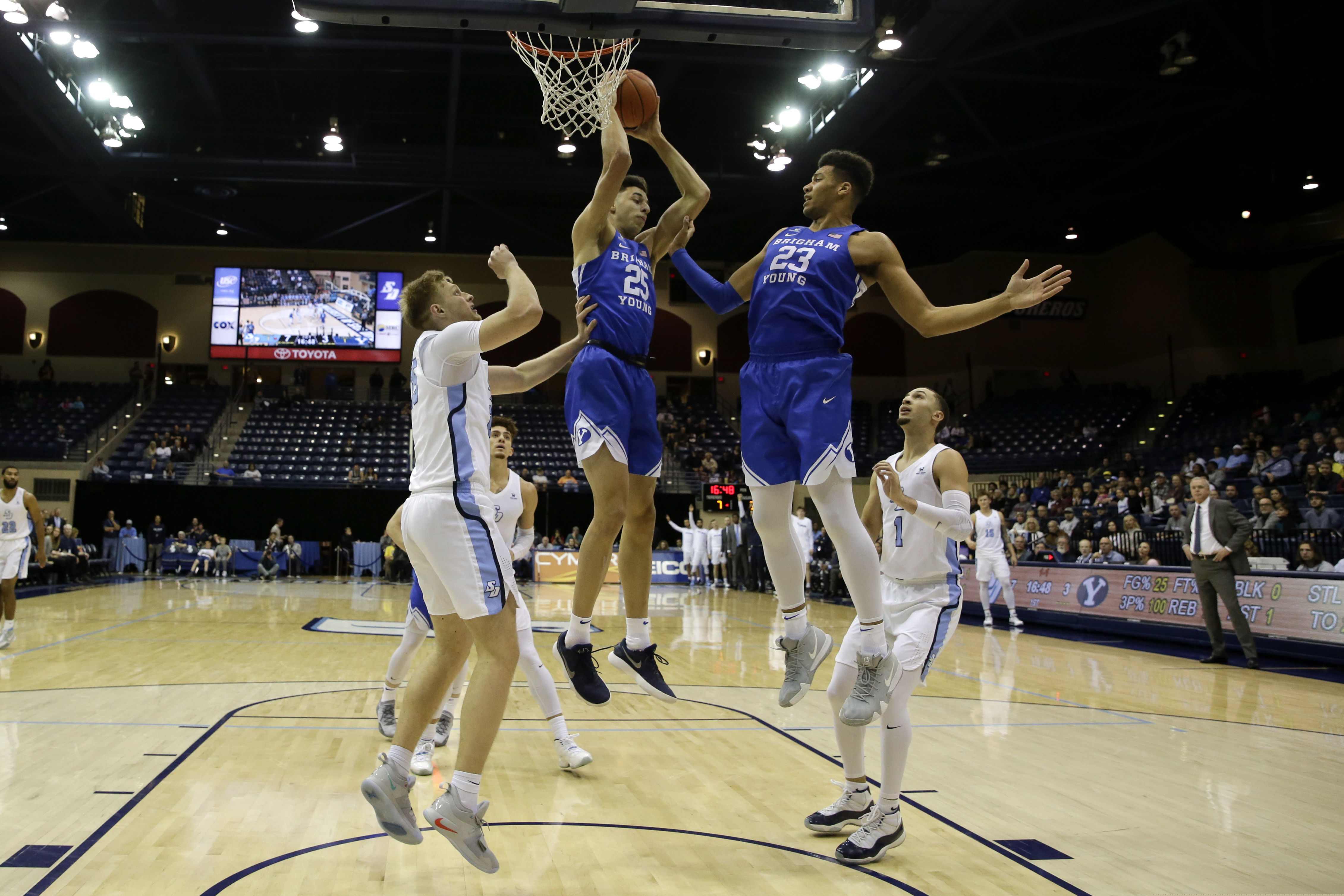 Brigham Young forward Gavin Baxter, center, grabs a rebound alongside teammate forward Yoeli Childs, right, as San Diego forward Yauhen Massalski defends, left, during the first half of an NCAA college basketball game Thursday, Feb. 14, 2019, in San Diego. (AP Photo/Gregory Bull)