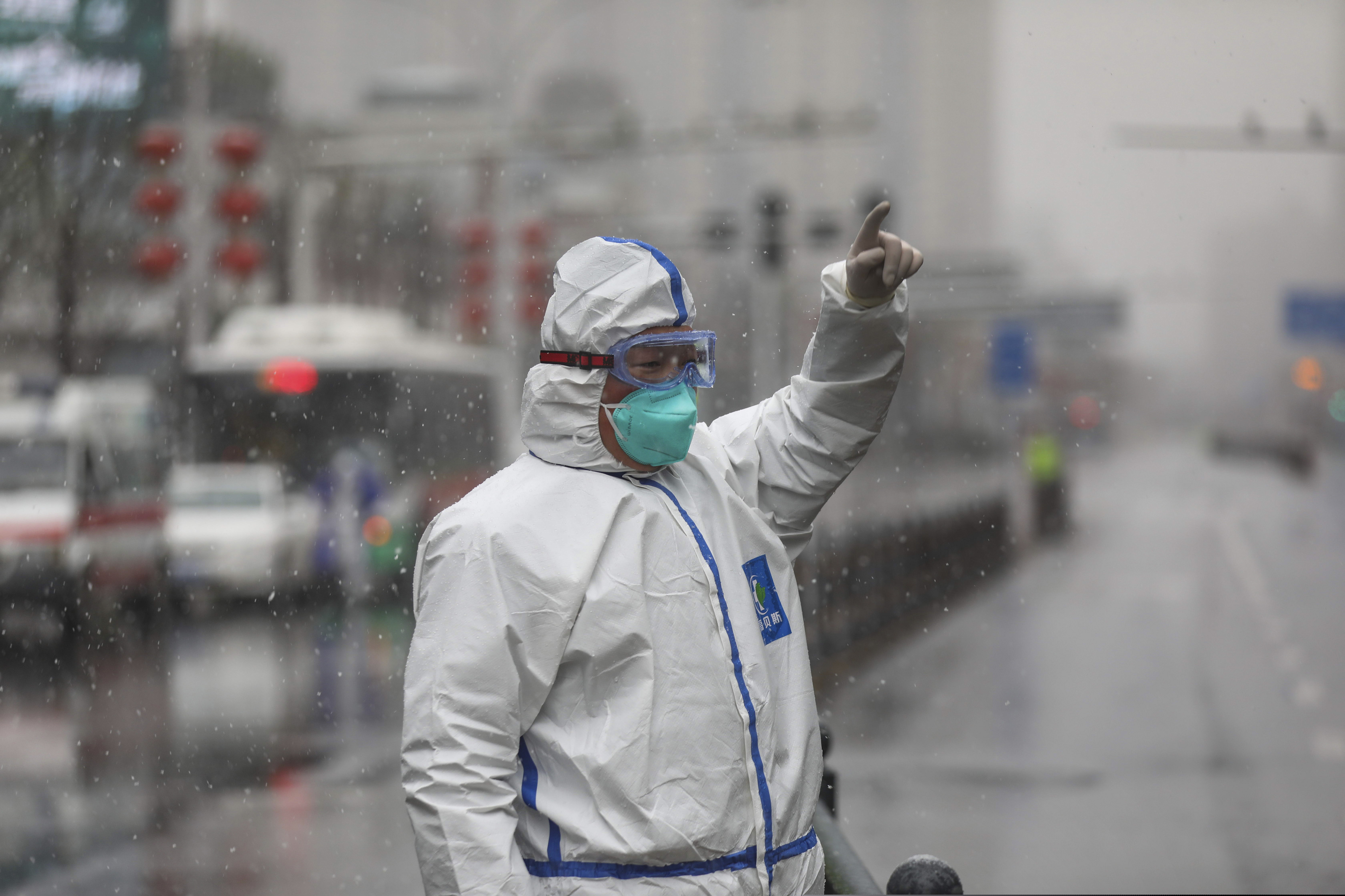 (Chinatopix via AP) A worker wearing a protective suit gestures to a driver outside a tumor hospital newly designated to treat COVID-19 patients in Wuhan in central China's Hubei Province, Saturday, Feb. 15, 2020. The virus is thought to have infected more than 67,000 people globally and has killed at least 1,526 people, the vast majority in China, as the Chinese government announced new anti-disease measures while businesses reopen following sweeping controls that have idled much of the economy.