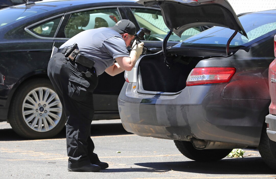 A police officer collects evidence in the parking lot of an apartment complex where Ayoola A. Ajayi was taken into custody in connection with missing University of Utah student Mackenzie Lueck Friday, June 28, 2019, in Salt Lake City.  Salt Lake City Police Chief Mike Brown said, Friday that Ajayi was being charged with aggravated murder, kidnapping and desecration of a body in the death of 23-year-old student. (AP Photo/Rick Bowmer)