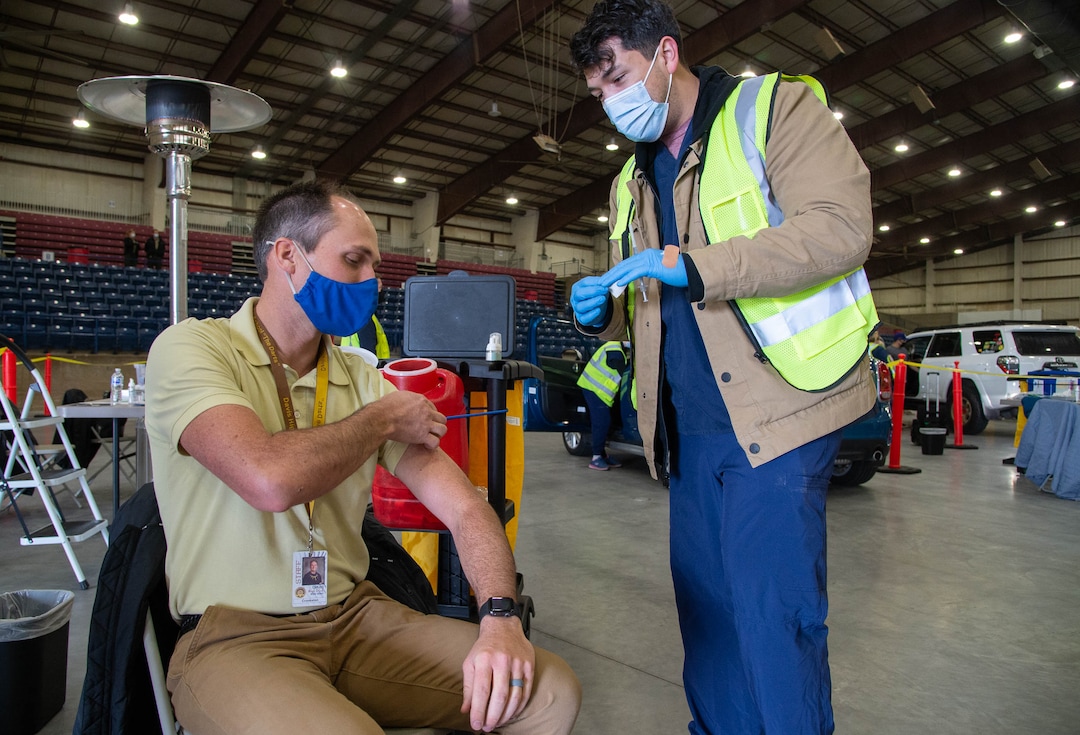 (Francisco Kjolseth  | The Salt Lake Tribune) Michael Crookston, Davis High band teacher, is vaccinated by registered nurse Bruno Gonzalez as the Davis County School District begins COVID-19 vaccinations for its teachers at the Davis County Legacy Center in Farmington on Tuesday, Jan. 12, 2021.