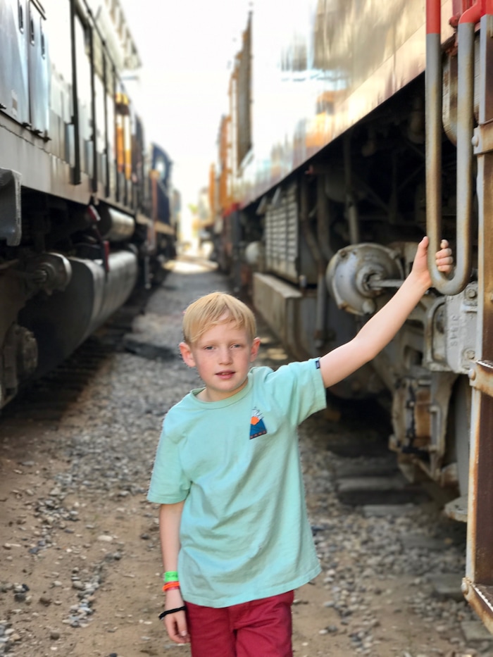 (Heather May | Special to The Tribune) Luke, 8, poses between retired locomotives at the Spencer S. Eccles Rail Center at the Ogden Union Station.