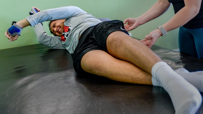 (Leah Hogsten  |  The Salt Lake Tribune) Stak works to roll his body onto his side into a sitting position with a finger push from his physical therapist. Audrick “Stak” Afatasi is fighting to regain movement in his lower body after being paralyzed at a trampoline park on March 15, 2019.