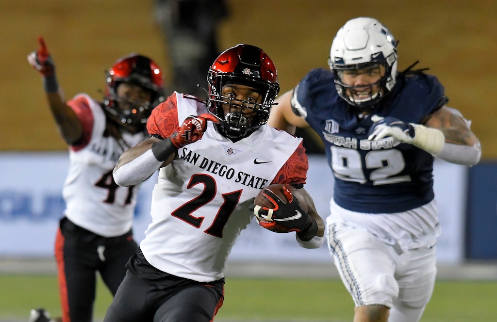 San Diego State running back Chance Bell (21) runs downfield as Utah State defensive lineman Hale Motu'apuaka (92) chases after him during the first half of an NCAA college football game Saturday, Oct. 31, 2020, in Logan, Utah. (Eli Lucero/The Herald Journal via AP, Pool)