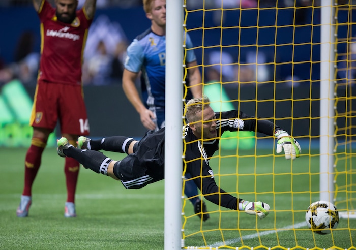 Vancouver Whitecaps goalkeeper David Ousted, front, dives but fails to stop the ball from entering the net for a goal credited to Real Salt Lake's Chris Wingert, not seen, during first half MLS soccer action in Vancouver, B.C., on Saturday, September 9, 2017. THE CANADIAN PRESS/Darryl Dyck/The Canadian Press via AP)