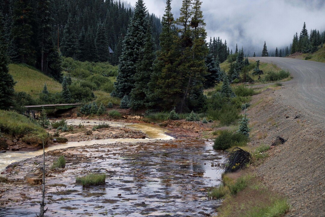 The Cement Creek flows down a valley a few miles downstream from the Gold King mine, where a wastewater accident several days earlier has raised alarm, outside Silverton, Colo., Wednesday, Aug. 12, 2015. The Environmental Protection Agency has taken full responsibility for the mine waste spoiling rivers downstream from Silverton, but people who live near the idled and leaking Gold King mine say local authorities and mining companies spent decades spurning federal cleanup help. (AP Photo/Brennan Linsley)