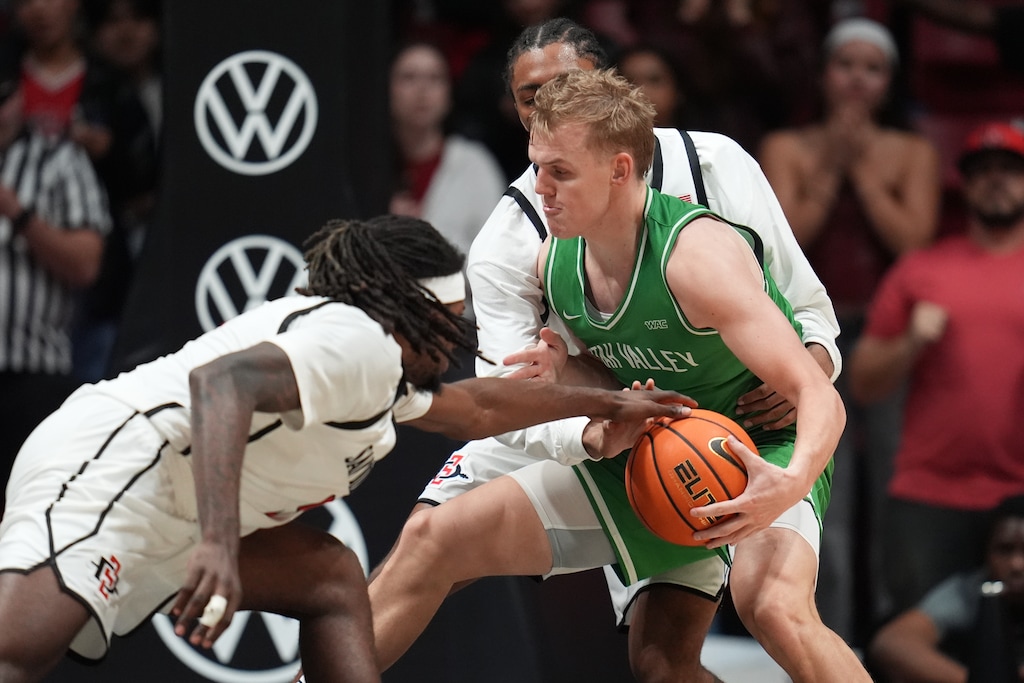(Gregory Bull | AP) Utah Valley guard Jackson Holcombe, center, tries to hold on to the ball as San Diego State forward Pharaoh Compton, front, and guard Taj DeGourville, behind, defend during a game on Dec. 3, 2025, in San Diego.