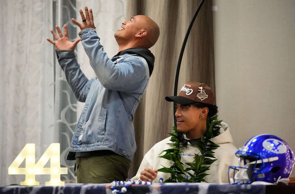 (Francisco Kjolseth | The Salt Lake Tribune) Uncle Muka Atiga throws his arms up in joking despair at having to cheer for BYU as his nephew Ephraim Asiata gets ready to sign his letter of commitment to play football for the Cougars on Tuesday, Dec. 19, 2023. The 3-star linebacker, one of Utah’s top prospects, made his choice, causing many of the Utah supporters in his family to joke about having to cheer for the rivalry team.