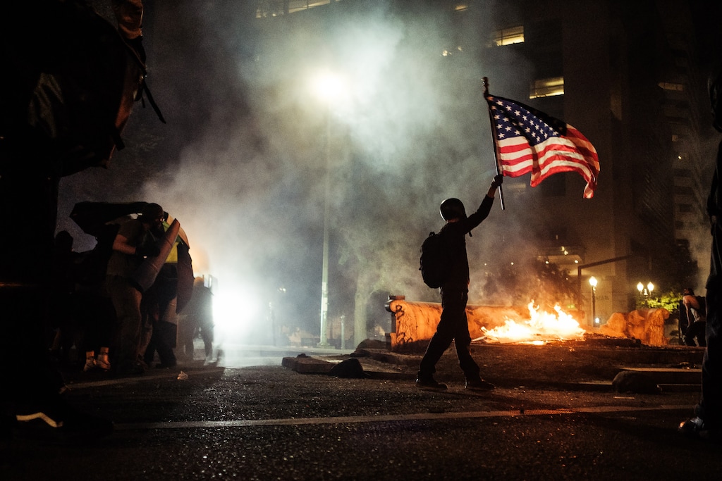 (Mason Trinca | The New York Times)

A protester carries an American flag during clashes with federal officers in Portland, Ore., early Tuesday, July 21, 2020. "Some presidents, when they get into trouble before an election, try to 'wag the dog' by starting a war abroad. Donald Trump seems ready to wag the dog by starting a war at home," writes New York Times columnist Thomas L. Friedman.