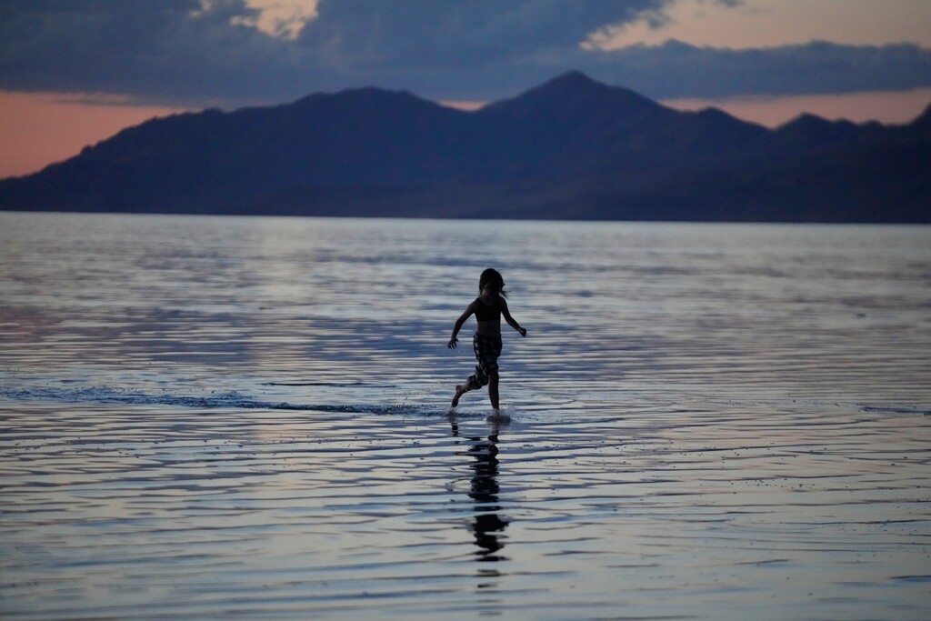 (Rick Bowmer | The Associated Press) A young person runs through the Great Salt Lake on June 15, 2023, near Magna, Utah.