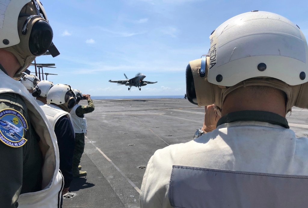FILE - In this file photo dated  Tuesday, April 10, 2018, Observers watch from the deck of the U.S. aircraft carrier Theodore Roosevelt as a U.S. F-18 fighter jet lands, in international waters off South China Sea.  According to a report released Wednesday May 2, 2018, the Swedish arms watchdog Stockholm International Peace Research Institute, or SIPRI, said Global military spending rose to $1.739 trillion in 2017, a 1.1 percent increase on 2016, China continued its upward trend, and the United States’ military spending remained constant for the second consecutive year. (AP Photo/Jim Gomez, FILE)