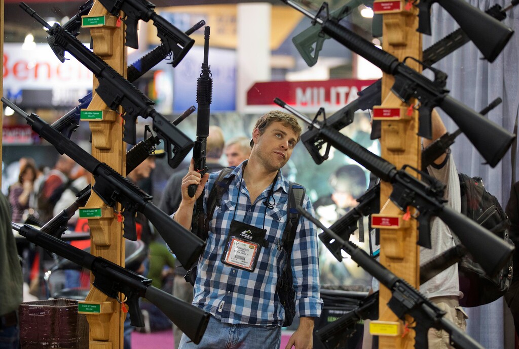 FILE - In this Jan. 17, 2013, file photo, Michael Kiefer, of DeFuniak Springs, Fla., checks out a display of rifles at the Rock River Arms booth during the 35th annual SHOT Show in Las Vegas. The largest gun industry trade show will be taking place in Las Vegas Jan. 23-26 just a few miles from where a gunman carried out the deadliest mass shooting in modern U.S. history. (AP Photo/Julie Jacobson, File)