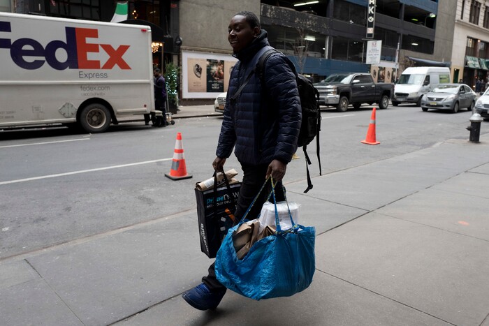 In this Wednesday, Dec. 20, 2017, photo, a delivery man carries customer orders as he leaves the Amazon Prime warehouse in New York. (AP Photo/Mark Lennihan)