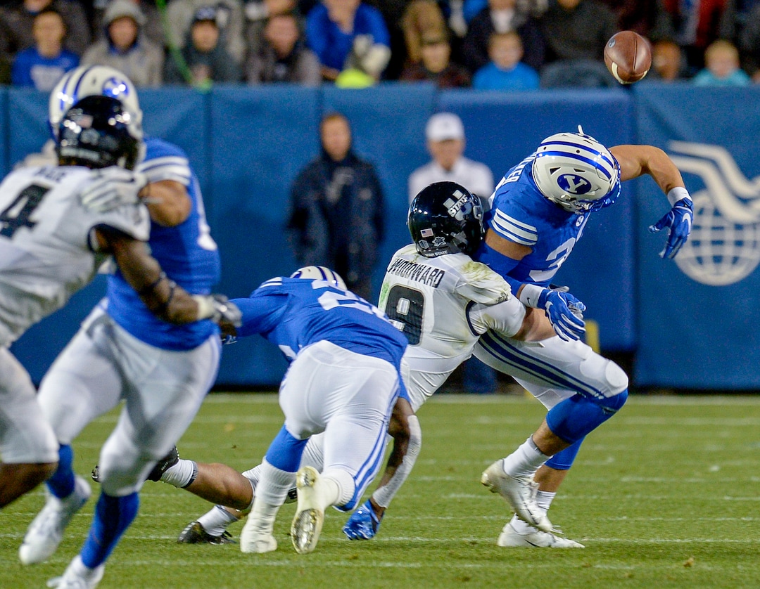 Leah Hogsten  |  The Salt Lake Tribune  The ball pops out of Brigham Young Cougars defensive back Dallin Holker's hands (32) as he is tackled by Utah State Aggies linebacker David Woodward (9) as BYU hosts Utah State University at Lavell Edwards Stadium in Provo, Friday, Oct. 5, 2018.