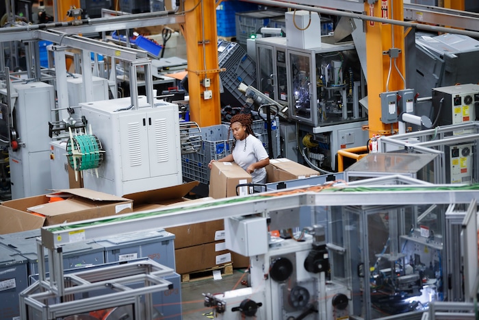 In this May 25, 2017 photo, an employee works on a factory floor at a Stihl Inc. production plant in Virginia Beach, Va. There are assembly lines at the Stihl plant, but human workers are interspersed with computers and robotics. (AP Photo/John Minchillo)