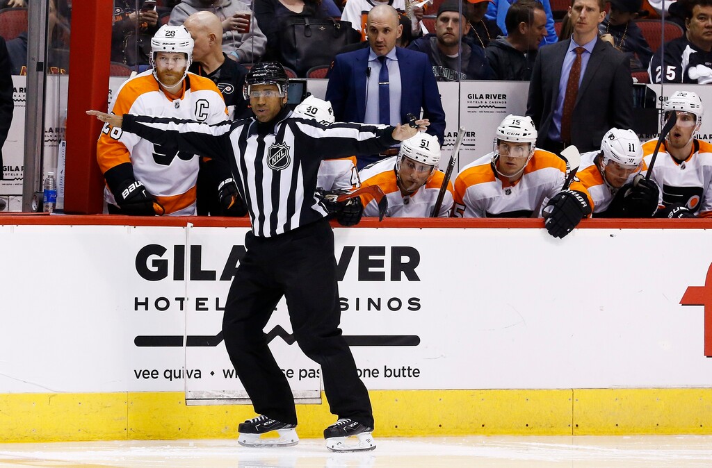 Linesman Shandor Alphonso signals a clean transition across the blue line during the third period of an NHL hockey game between the Arizona Coyotes and the Philadelphia Flyers Saturday, Feb. 10, 2018, in Glendale, Ariz. The NHL has almost two dozen black players but just one black official in linesman Shandor Alphonso and one black coach in Flames assistant Paul Jerrard. Alphonso, Jerrard and recently retired linesman Jay Sharrers hope they can show young minorities they can stay in hockey beyond playing. (AP Photo/Ross D. Franklin)