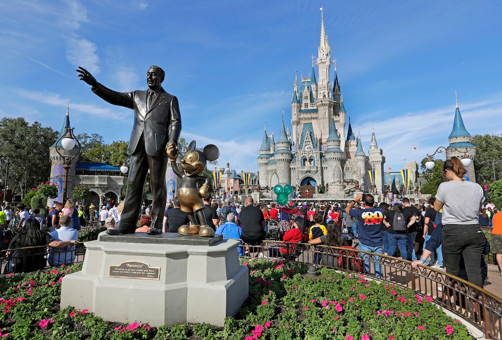 (John Raoux | AP file photo) Guests watch a show near a statue of Walt Disney and Micky Mouse in front of the Cinderella Castle at the Magic Kingdom at Walt Disney World in Lake Buena Vista, Fla.