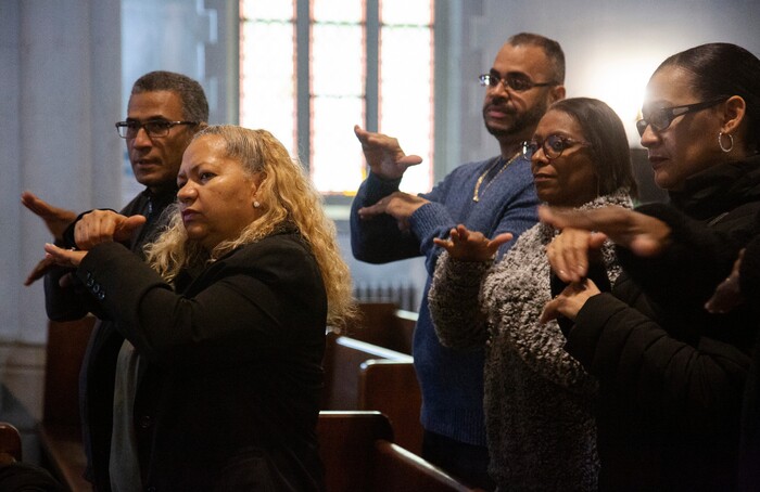 In this Sunday, Dec. 15, 2019, photo, worshippers Carlos Tirado, left, and Lidia Martinez, second from left, sign in response to a sermon at Holyrood Episcopal Church-Iglesia Santa Cruz in New York. Tirado and Martinez, who are deaf, began attending the church last year after seeing the Rev. Maria Santiviago give sermons in sign language. (AP Photo/Jessie Wardarski)