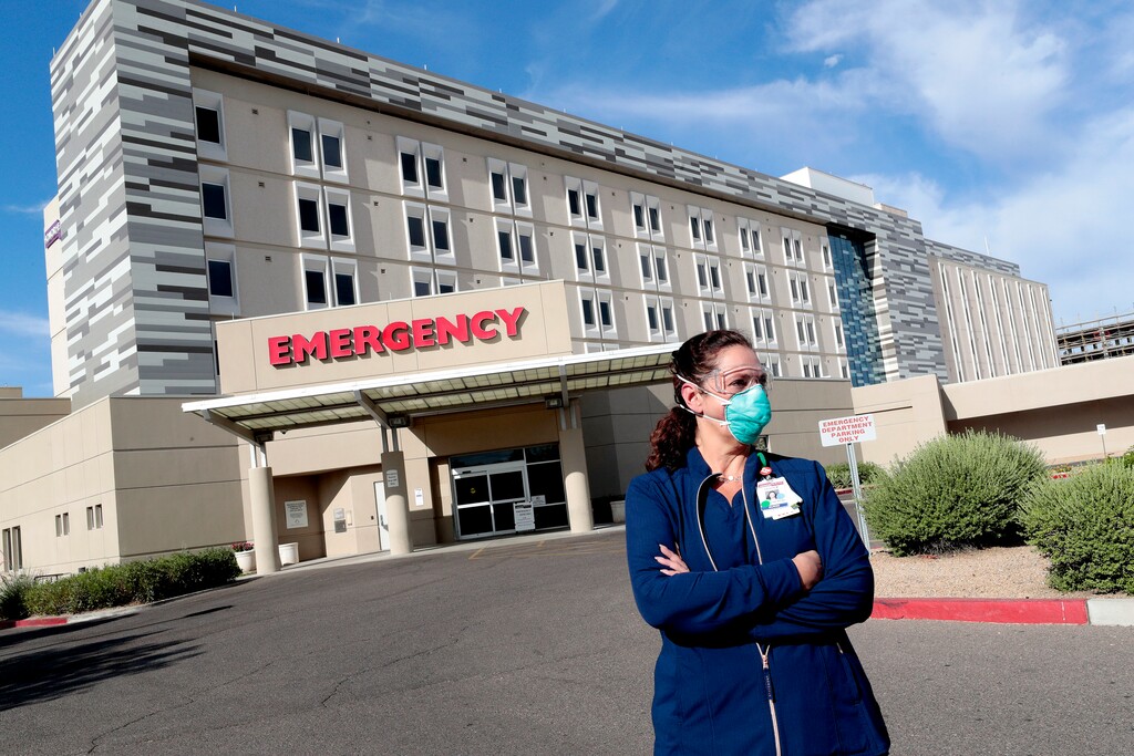 Caroline Maloney stands outside HonorHealth's Scottsdale Osborn Medical Center at the end of her overnight shift early Friday, June 26, 2020 in Scottsdale, Ariz. Arizona nurses and doctors find themselves on the frontline as the coronavirus rips through the state, making it one of the world's hot spots. (AP Photo/Matt York)
