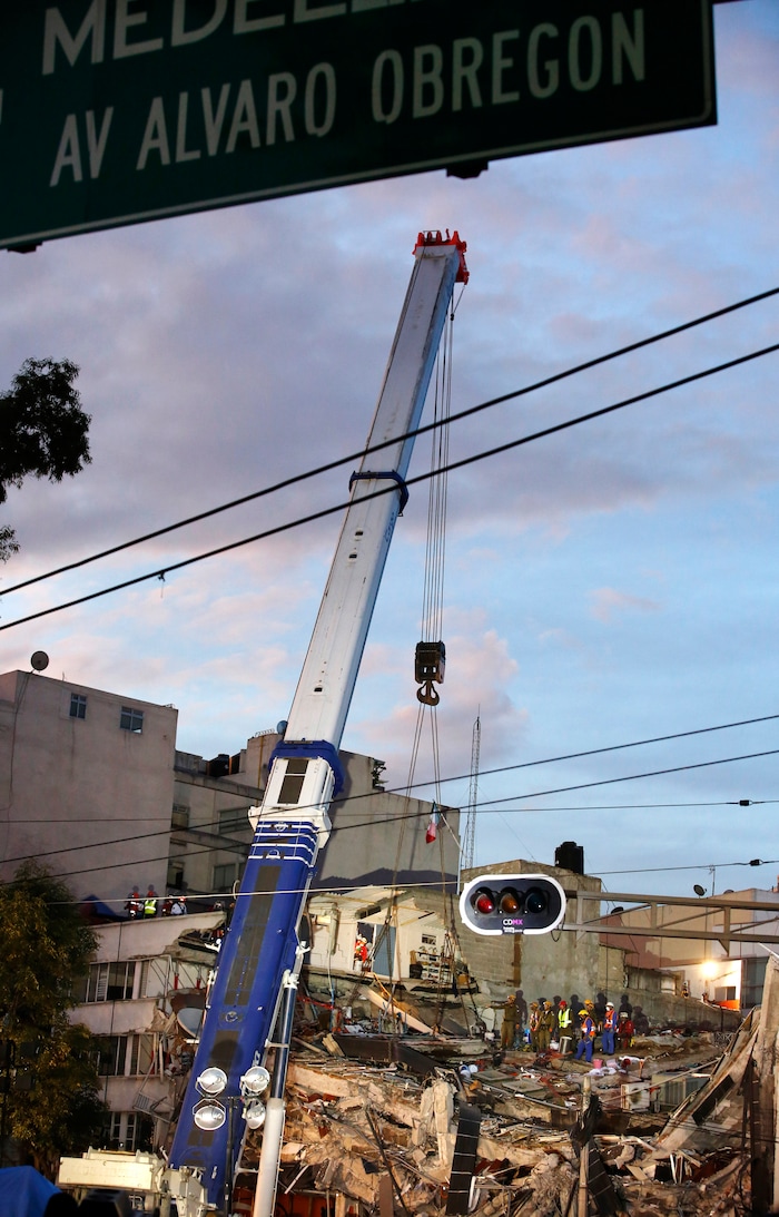 Israeli and Mexican rescue workers use a crane to lift a section of a felled building as rescue workers race against the clock to reach possible survivors trapped inside the office building on Alvaro Obregon Avenue in the Roma Norte neighborhood of Mexico City, at sunrise on Saturday, Sept. 23, 2017. A strong new earthquake shook Mexico on Saturday morning, causing street signs around the collapsed building to sway and rescue workers to evacuate the site temporarily. (AP Photo/Rebecca Blackwell)