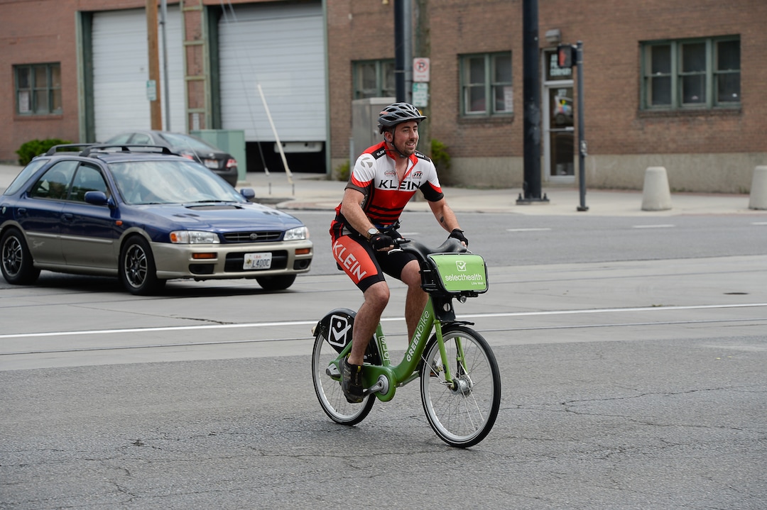 (Francisco Kjolseth  |  The Salt Lake Tribune)  Salt Lake Tribune reporter Ben Wood nears the finish line on his Green Bike during a race against colleagues with different forms of downtown transportation from Library Square to the Tribune building at the Gateway on Thursday, Aug. 2, 2018. Modes of transportation included, rentable electric scooters, Green Bike, TRAX, Lyft, and walking.