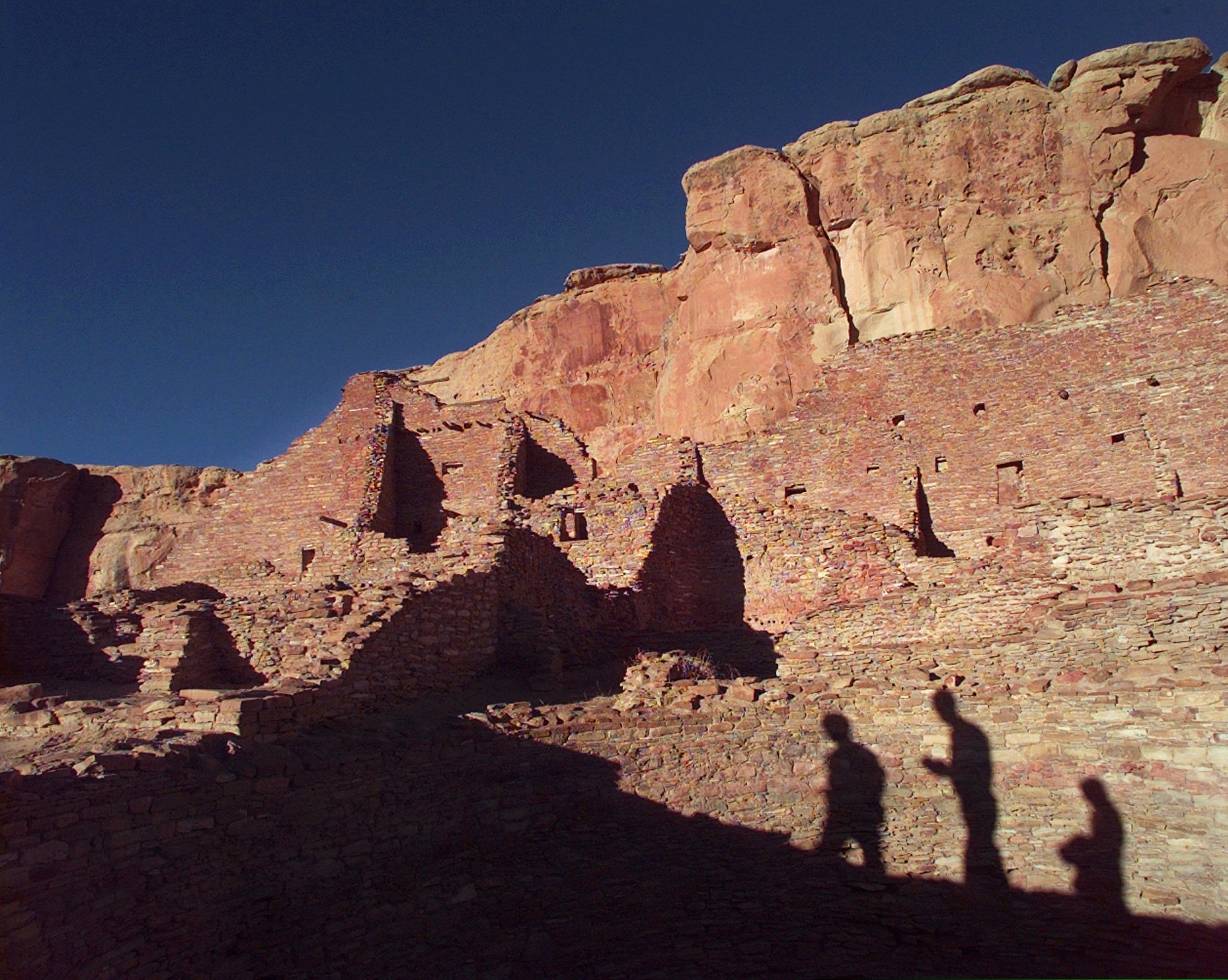 (Eric Draper | Associated Press file photo) In this Nov. 21, 1996, photo, tourists cast their shadows on the ancient Anasazi ruins of Chaco Culture National Historical Park in New Mexico. Advocates for greater restrictions on oil and natural gas drilling near ancient Native American cultural sites in the Southwest are urging Congress to establish new precautions. A congressional subcommittee on energy ventured thousands of miles from Washington to hold a field hearing Monday, April 15, 2019, on the impacts of air pollution on sacred ruins and landmarks. New Mexico's delegation to Washington wants to halt new drilling leases near Chaco Culture National Historic Park.