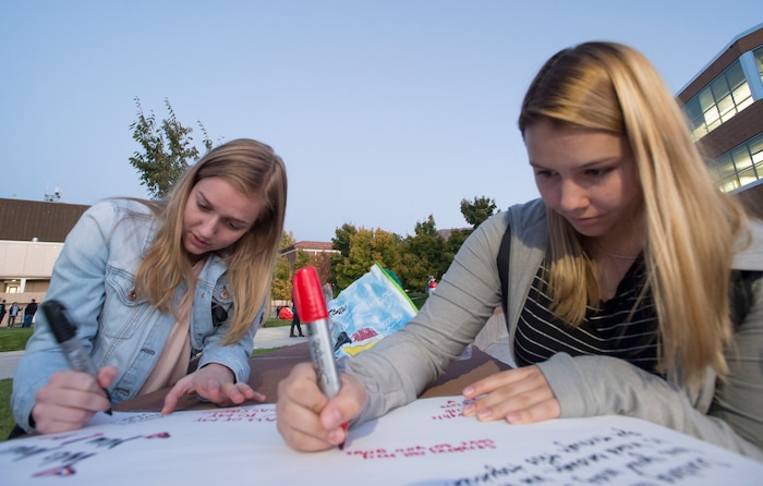 (Rick Egan  |  The Salt Lake Tribune)  Southern Utah University students Nikki Sander (left) and Lena Edman sign a poster for students at UNLV, during a candle light vigil for the victims of the Las Vegas shooting, on the SUU campus in Cedar City, Wednesday, October 4, 2017.