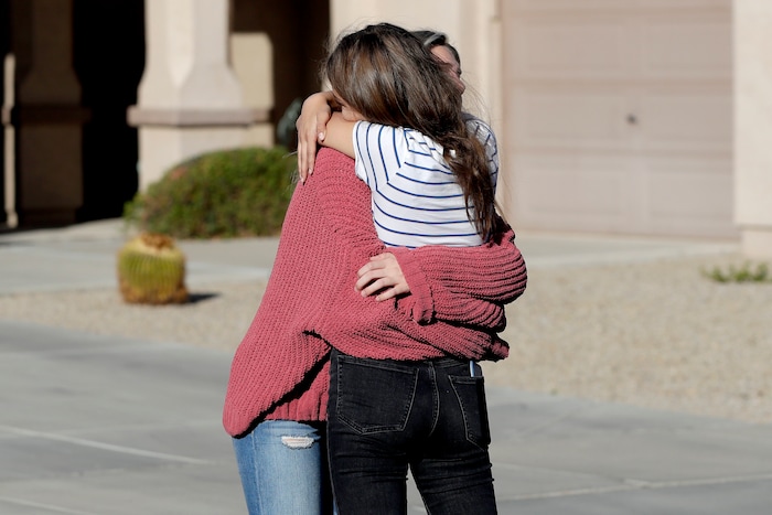 Madelyn Staddon, right, a relative of some of the members of a Mormon community who were attacked while traveling near the US-Mexico border, embraces a neighbor outside her home, Tuesday, Nov. 5, 2019, in Queen Creek, Ariz. Drug cartel gunmen ambushed three vehicles along a road near the state border of Chihuahua and Sonora on Monday, slaughtering at least six children and three women from the extended LeBaron family, all of them U.S. citizens living in northern Mexico, authorities said Tuesday. (AP Photo/Matt York)