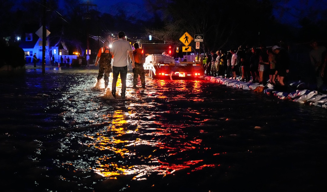 (Francisco Kjolseth | The Salt Lake Tribune) People work to protect homes into the night along 1700 South in Salt Lake City from the rising flow of Emigration Creek through Wasatch Hollow Park on Wednesday, April 12, 2023. 
