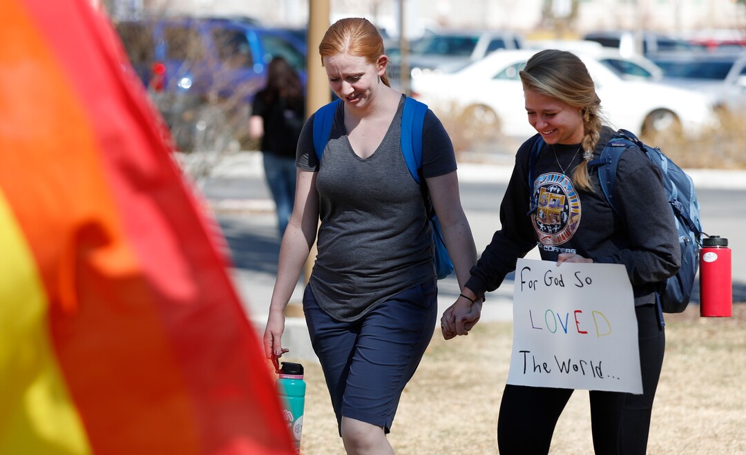 (George Frey  |  special to The Salt Lake Tribune) Two girls hold hands in front of the Ernest L. Wilkinson Student Center on the campus of Brigham Young University as part of a protest of BYUÕs rollback of a newly announced policy change on LGBTQ students on March 5, 2020 in Provo, Utah.
